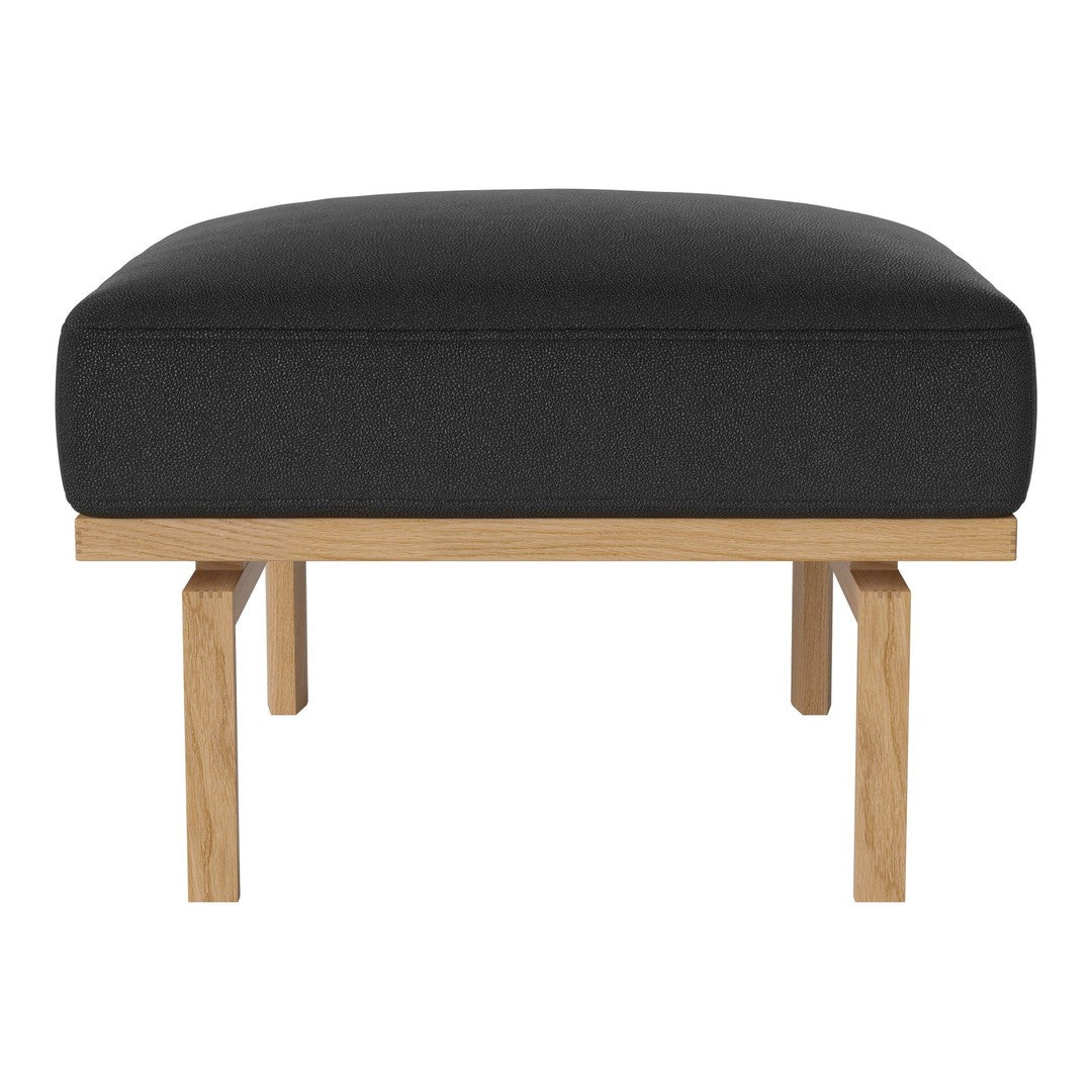 Black upholstered ottoman with a minimalist oak wood frame, showcasing a sleek modern design.