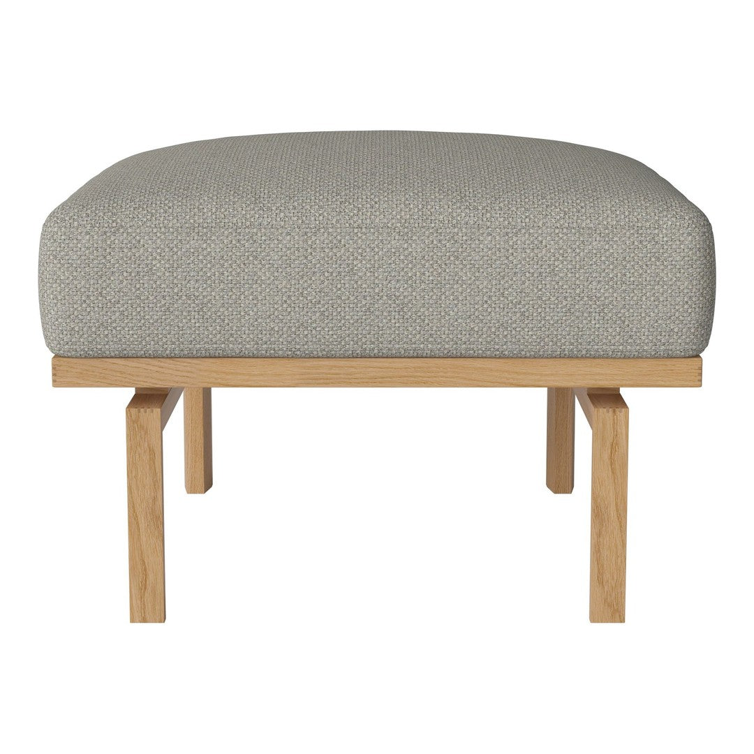 Light grey patterned upholstery on a curved ottoman with natural wood legs. Modern and stylish design for any space.