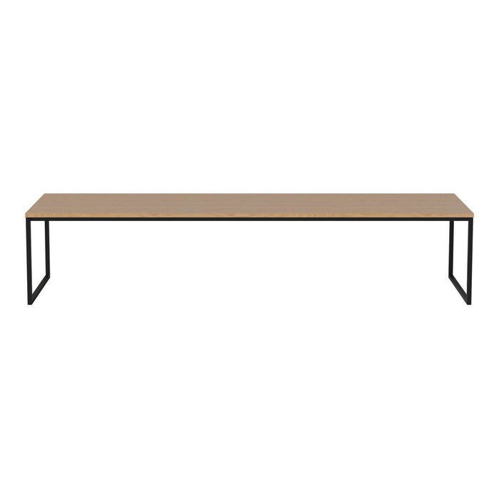 Long wooden tabletop in a natural finish with minimalist black metal legs, creating a sleek and modern look.