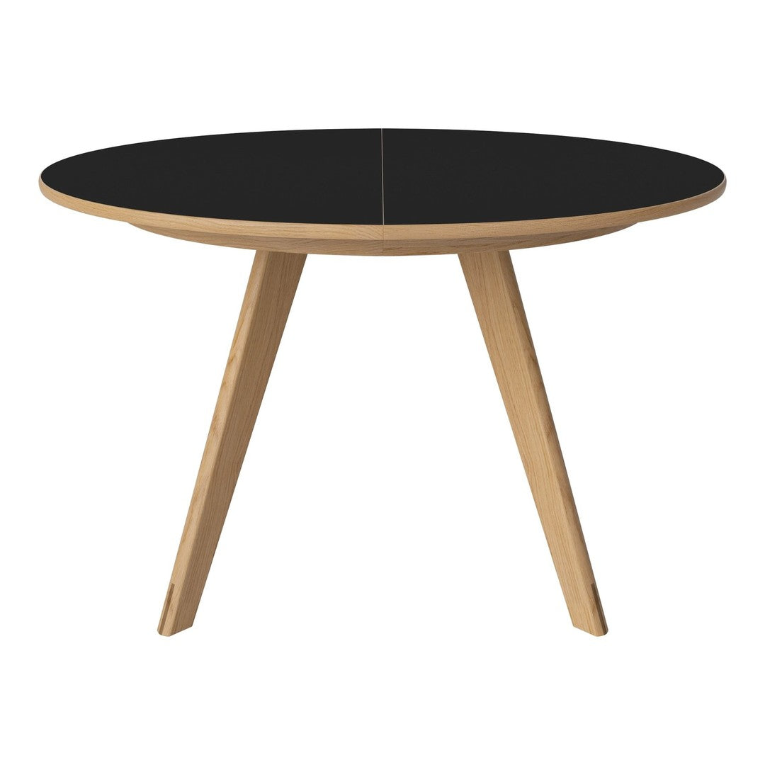 Round table with a sleek black top and natural wood legs, perfect for modern decor.