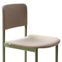 Minimalist green metal chair with a soft beige fabric seat and backrest, featuring a textured pattern.