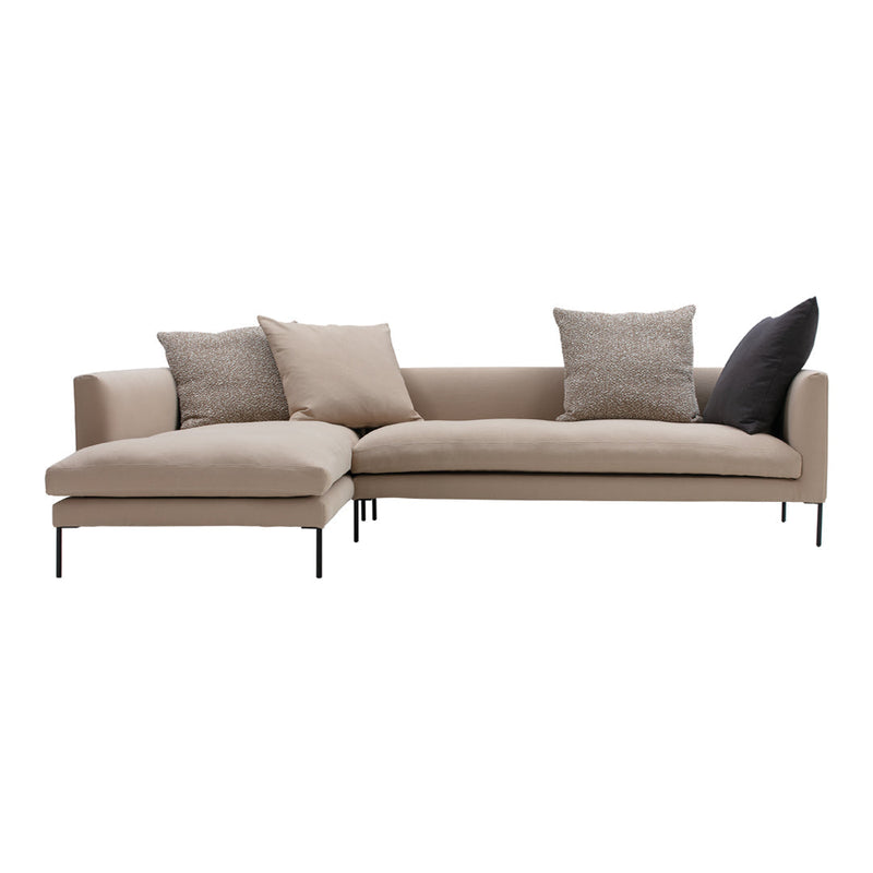 Beige sectional sofa with textured throw pillows in gray and black, featuring sleek black metal legs.