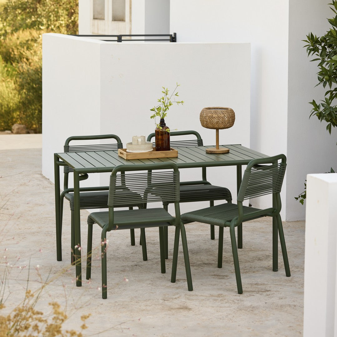 Green metal outdoor dining set with minimalist design, featuring a textured tabletop and matching chairs in a serene setting.