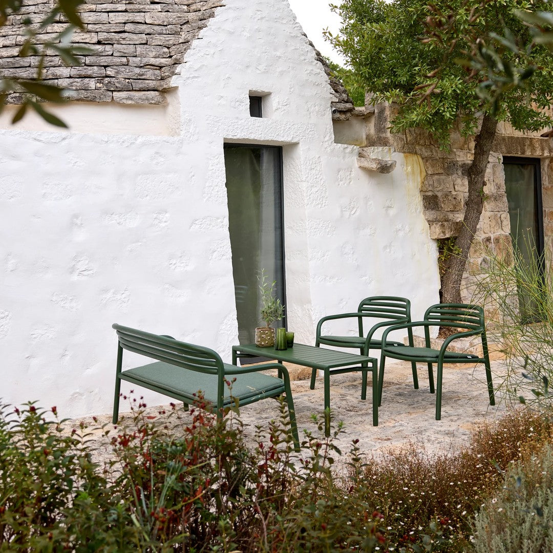 Green outdoor seating set against a white stone backdrop, featuring clean lines and minimalist patterns. Ideal for patios.