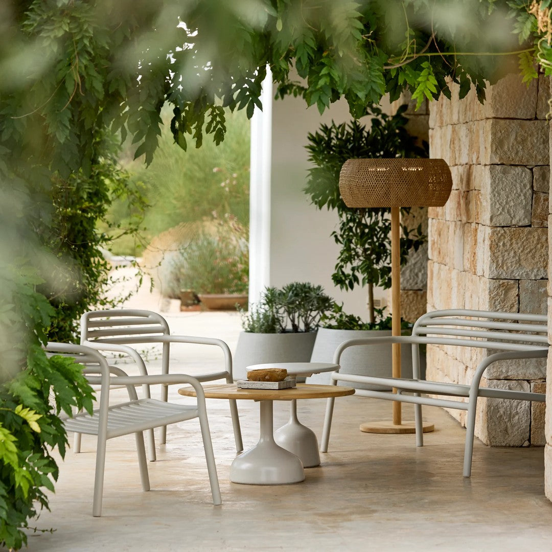 Stylish white metal outdoor furniture with natural wood accents in a serene, greenery-filled setting.
