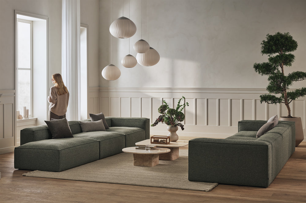Modern living room with a green sectional sofa, coffee table, and decorative elements by BOLIA.
