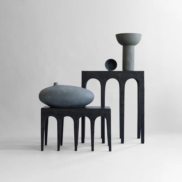 Stylish monochrome ceramic vases in shades of gray, featuring smooth and textured surfaces with architectural patterns.