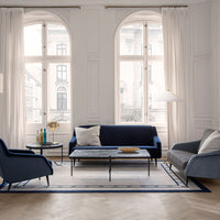 Navy blue and light gray sofa set on a patterned rug with clean lines, surrounded by bright natural light.