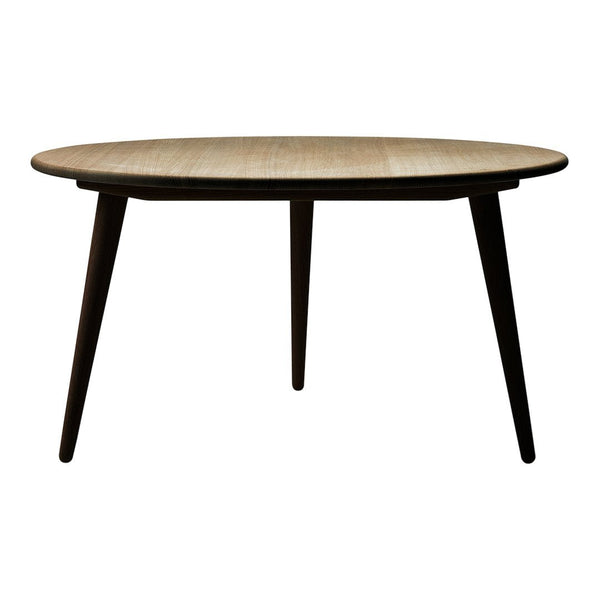 Round wooden dining table with a light oak finish and dark tapered legs, showcasing a modern minimalist design.