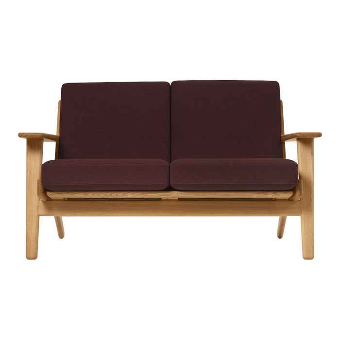 Maroon cushions on a light wooden frame sofa, featuring a simple, modern design and clean lines.