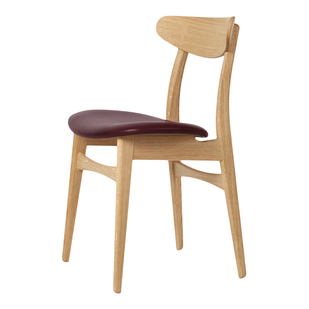 Light oak chair with a smooth, curved back and a rich burgundy seat, showcasing modern design and natural tones.
