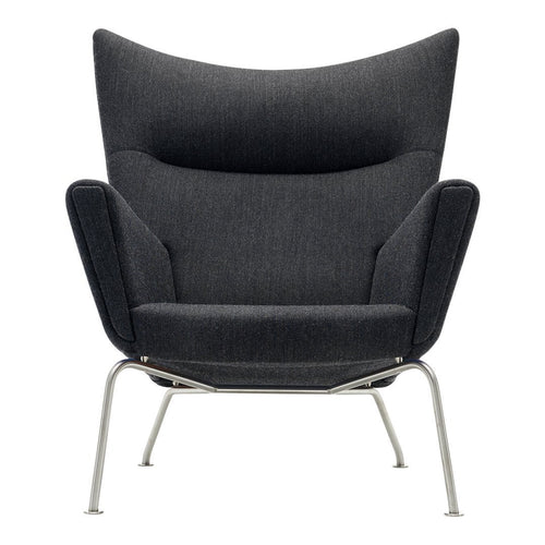 Modern dark gray armchair with a sleek, textured fabric and minimalist silver legs, featuring a stylish wingback design.