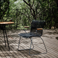 Black striped chair with wooden armrests, set against a natural green background and wooden deck.