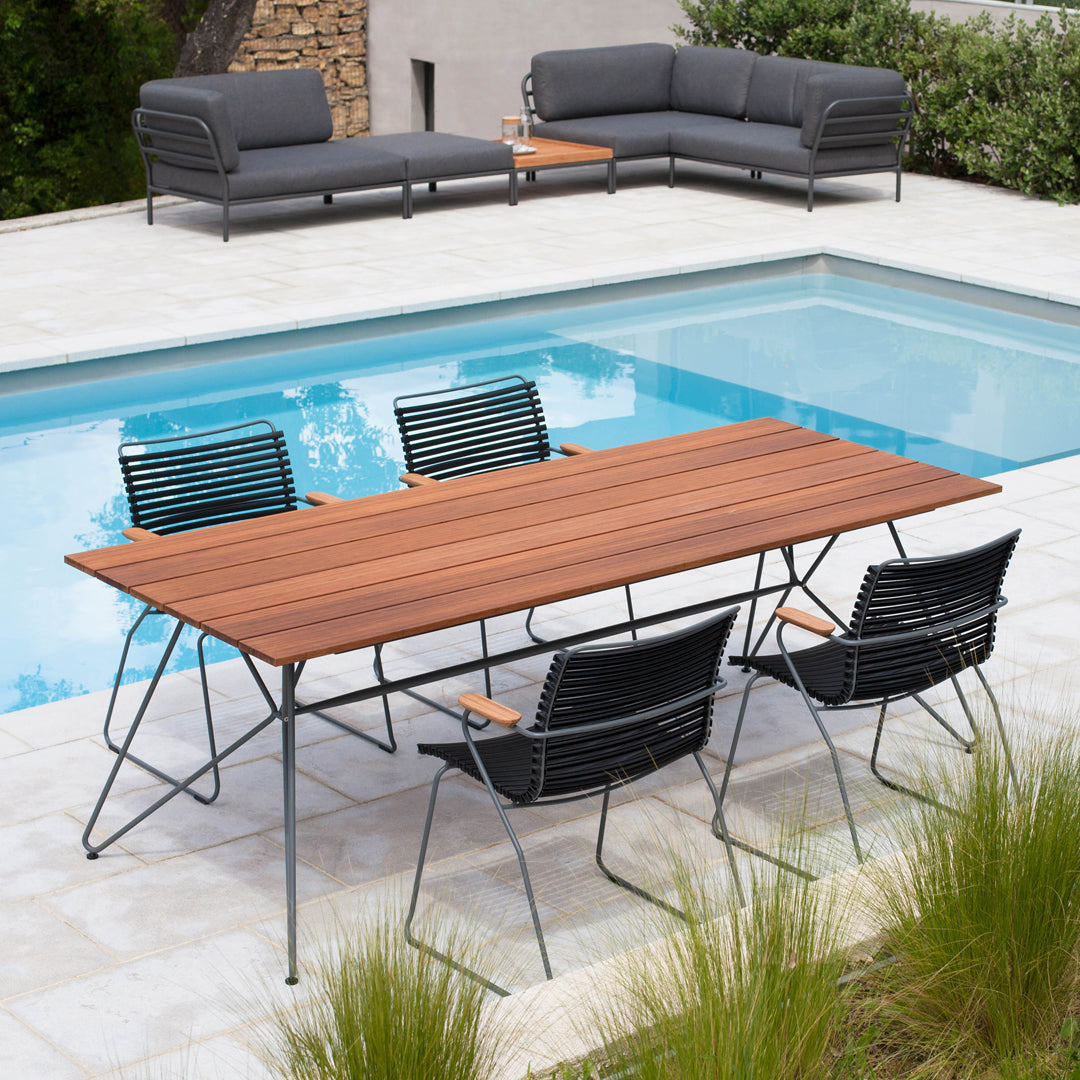 "Elegant outdoor dining set featuring a wooden table with a slatted design and black striped chairs by a poolside."