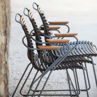 Stacked outdoor chairs in dark gray with natural wood accents, featuring a sleek, modern design and curved patterns.