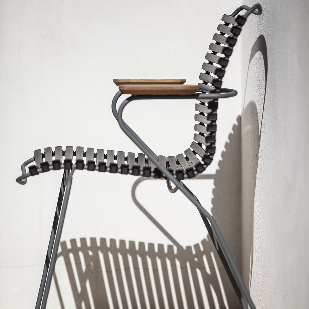 Gray and black patterned chair with a natural wood accent, casting intriguing shadows against a light wall.