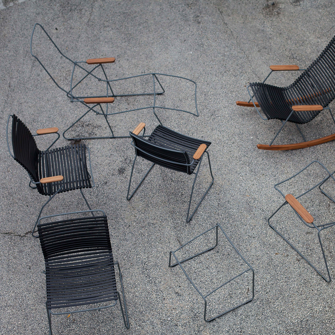 "Collection of modern black wire chairs with natural wood accents on a textured gray surface."