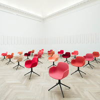 Colorful modern chairs in shades of red, orange, and peach set against a bright, minimalist backdrop.