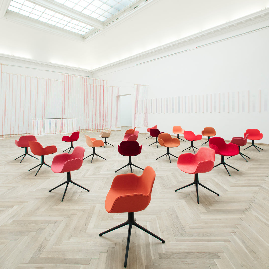 Colorful chairs in shades of red and orange with sleek black bases arranged in a modern, minimalist space.