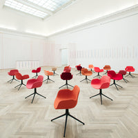Colorful chairs in shades of red and orange with sleek black bases arranged in a modern, minimalist space.