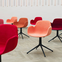 Colorful chairs in shades of red, coral, and orange with modern plush upholstery and sleek black bases.
