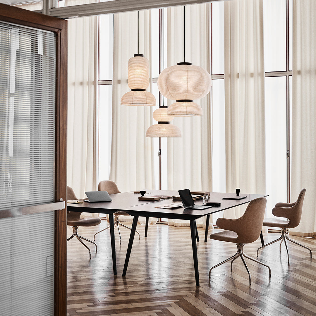 Modern office with wooden floors, beige chairs, and soft white pendant lighting in a bright, airy space.