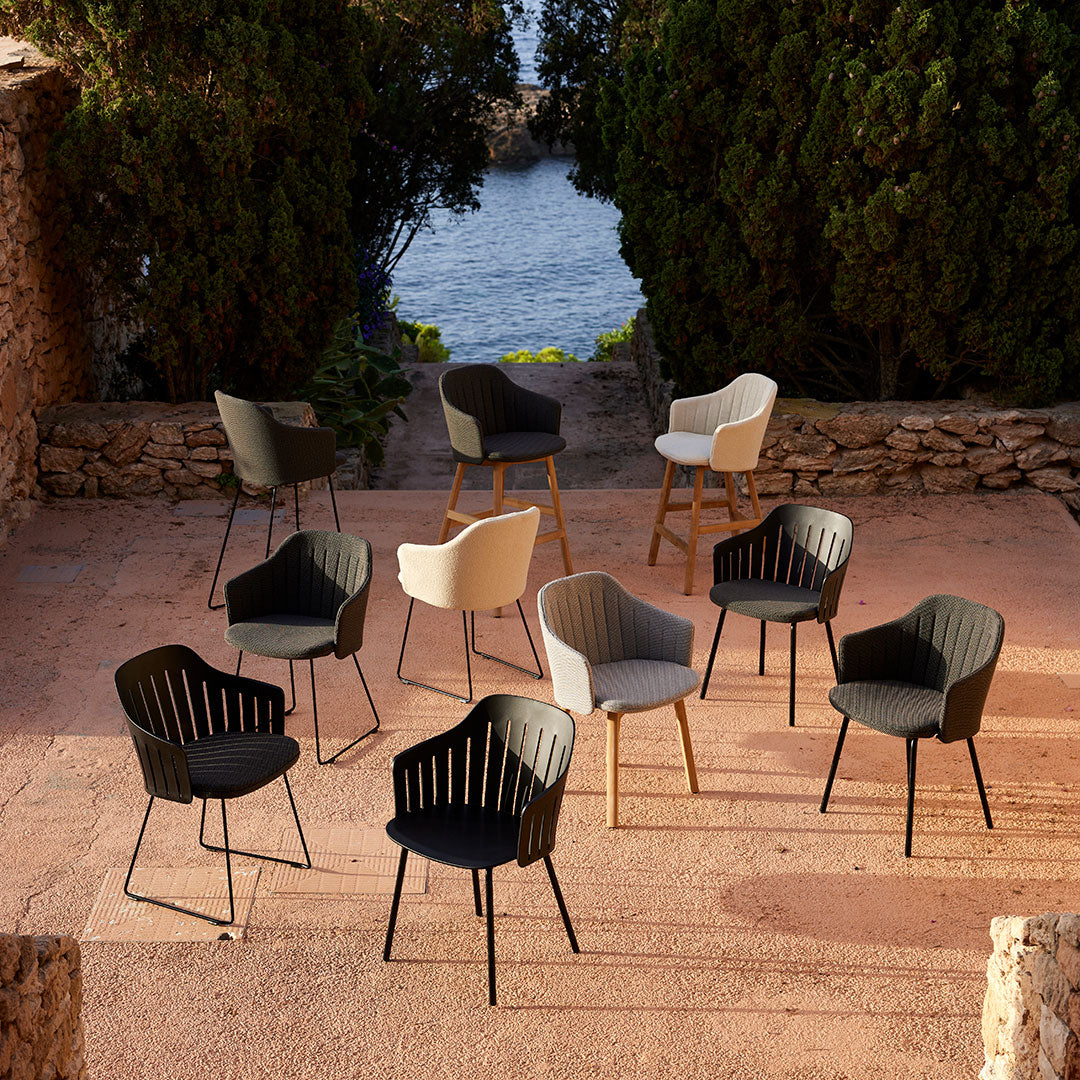 Set of modern chairs in black, white, and grey with ribbed patterns, arranged outdoors against a natural backdrop.