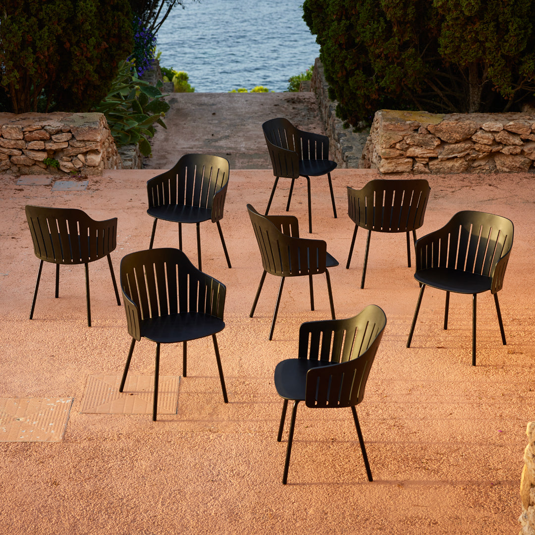Black slatted chairs arranged outdoors on a sunlit terrace, showcasing modern design and sleek lines.