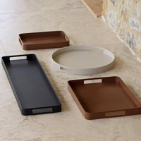 Set of four elegant trays in brown, black, and gray. Sleek, modern designs with smooth finishes and unique shapes.