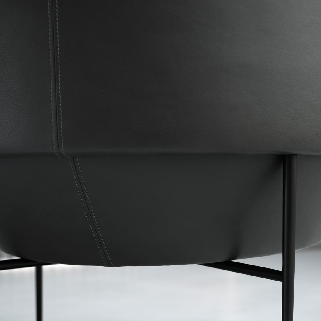 Black leather chair with subtle stitching details and a sleek modern design, set on thin black metal legs.