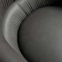 Smooth black leather upholstery with subtle ridges and curves, showcasing a modern and elegant design.