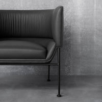 Stylish black leather sofa with vertical ribbed pattern and sleek metallic legs, set against a grey background.