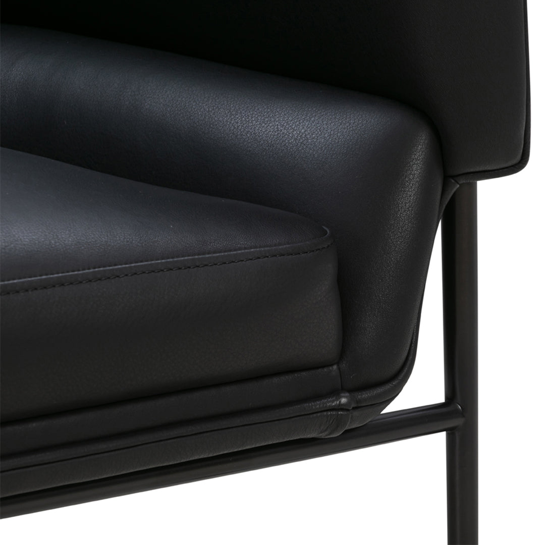 Black leather armchair seat with smooth texture and minimalist black metal frame. Elegant and modern design.