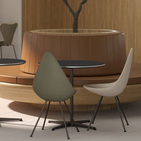 Elegant olive green and soft beige chairs around a sleek black table, set against a warm wooden backdrop.