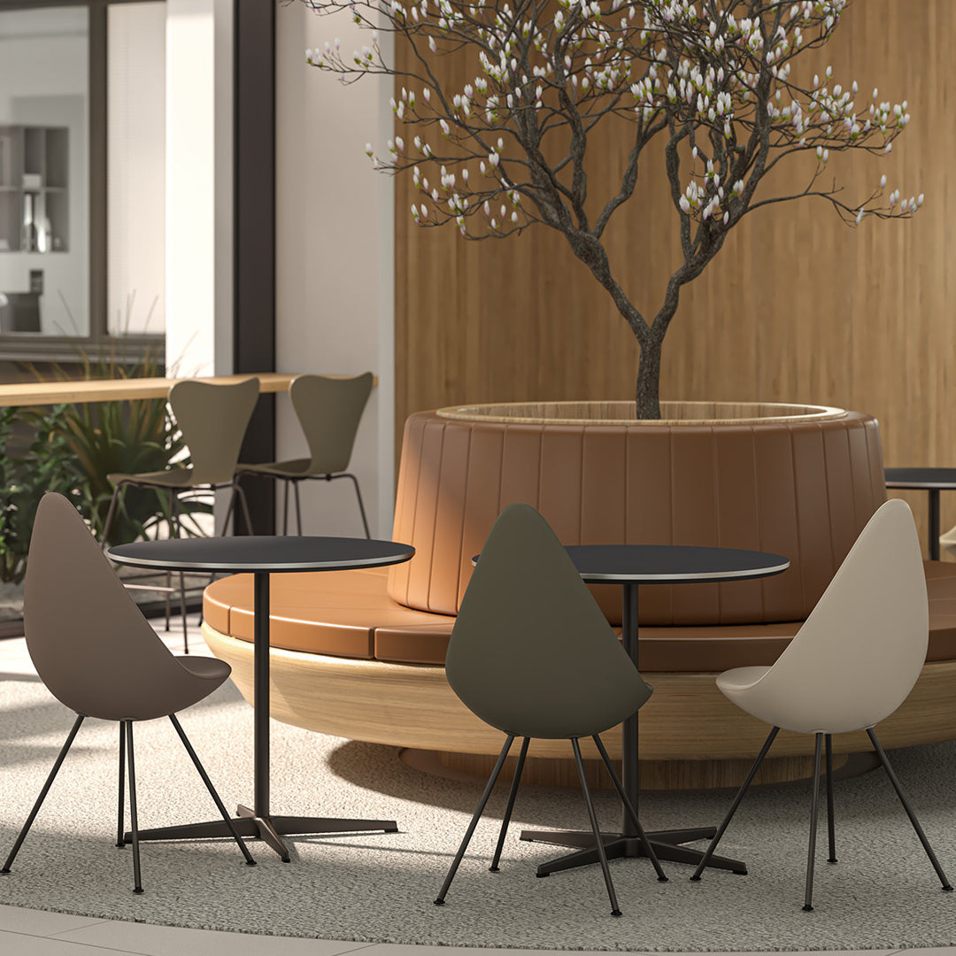 Multicolored chairs in earthy tones surround black tables, set against a natural wood backdrop and soft, patterned flooring.