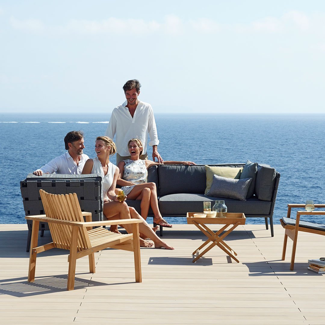 "Modern outdoor furniture set featuring neutral tones and textured fabrics against a serene coastal backdrop."