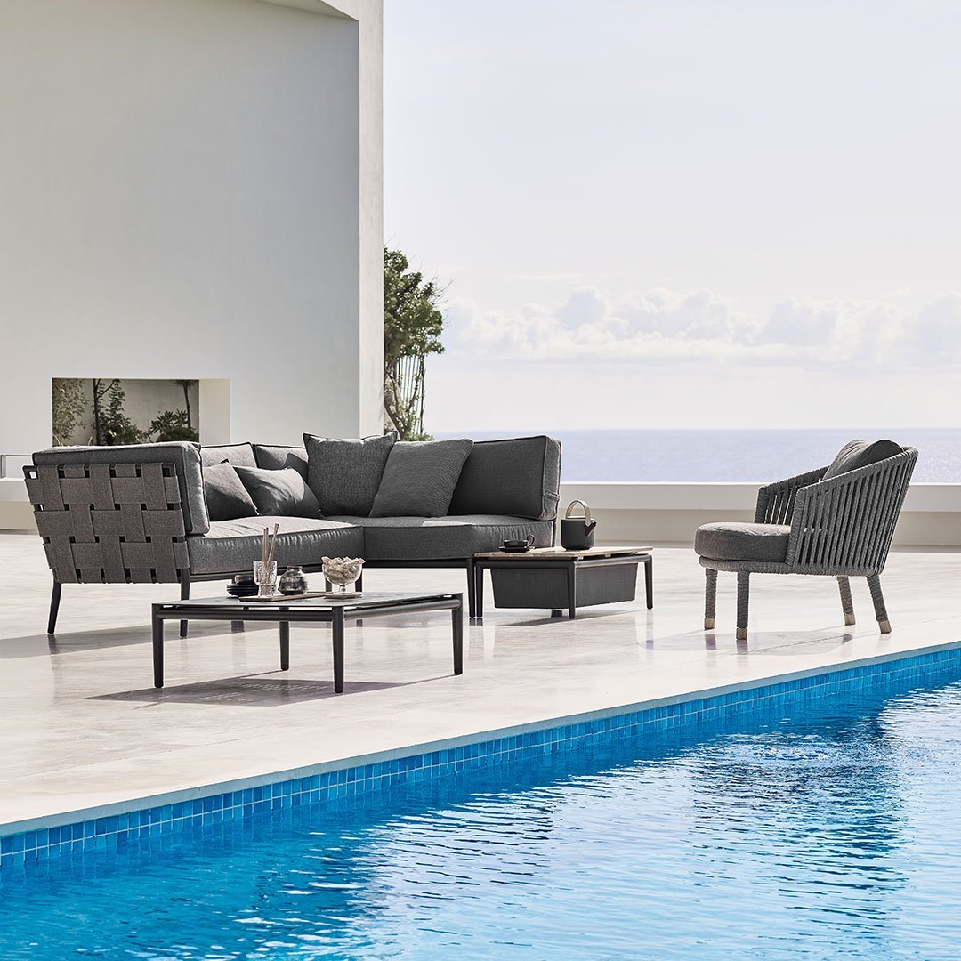 "Modern gray outdoor furniture set with tufted cushions, sleek lines, and stylish patterns by the pool."