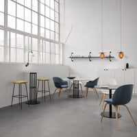 Modern dining setup featuring blue and grey chairs, white tables, and warm wood accents in a minimalist space.