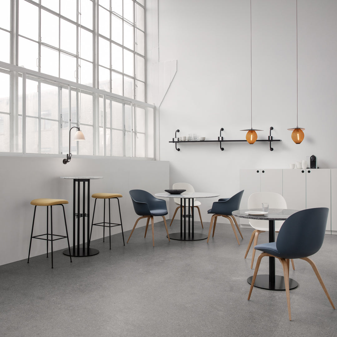 Modern dining setup featuring blue and grey chairs, white tables, and warm wood accents in a minimalist space.