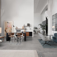 Modern office space featuring gray walls, wooden accents, blue seating, and light-colored textiles. Minimalist design.