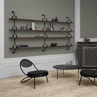 Modern black shelves with wooden accents against a soft green wall, paired with a black chair and coffee table.
