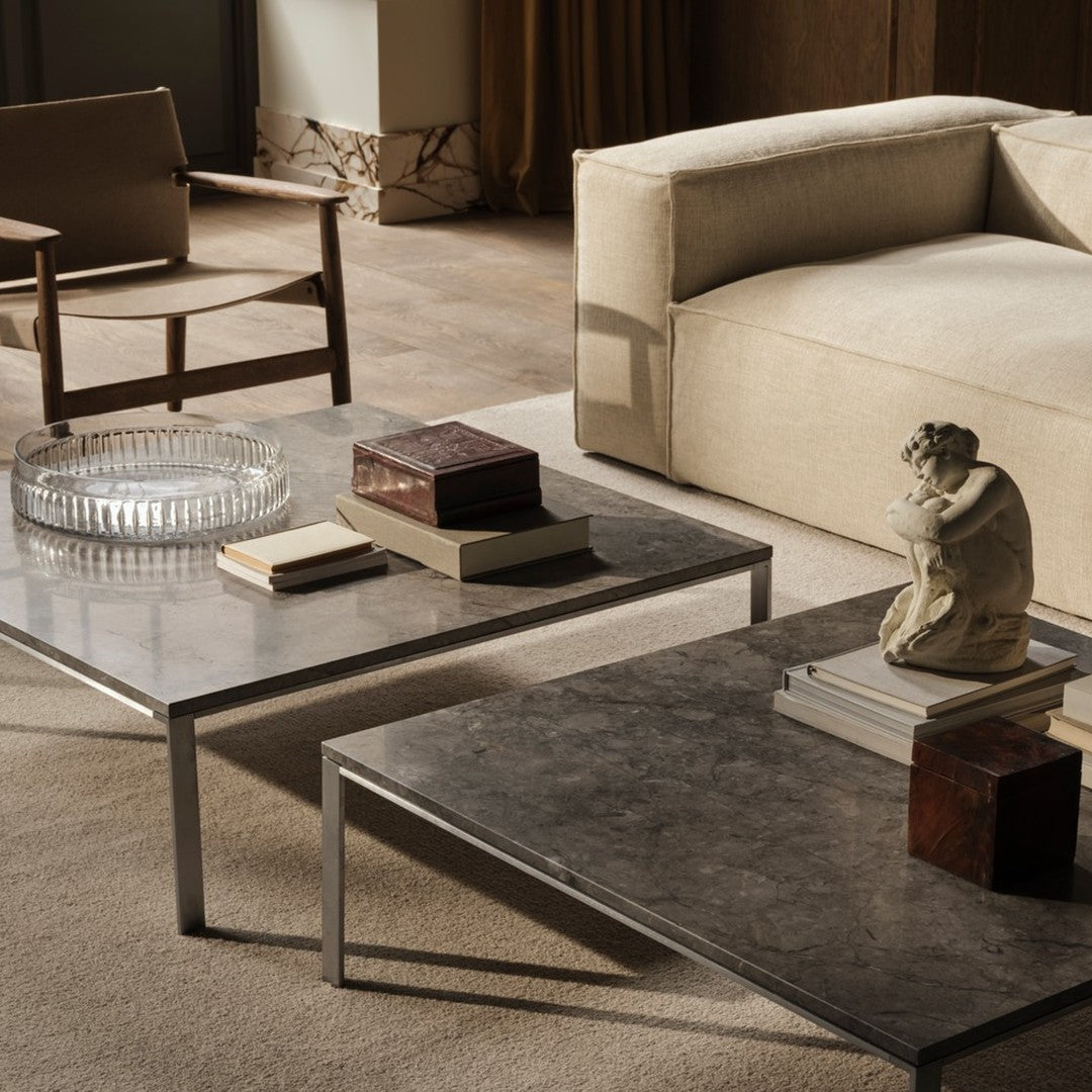 Modern coffee tables with a sleek gray surface and metallic accents, styled with books and decorative objects.