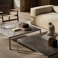 Modern coffee tables with a sleek gray surface and metallic accents, styled with books and decorative objects.