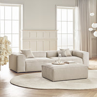 Light beige textured sectional sofa with matching ottoman on a soft cream circular rug, set in a bright, airy room.