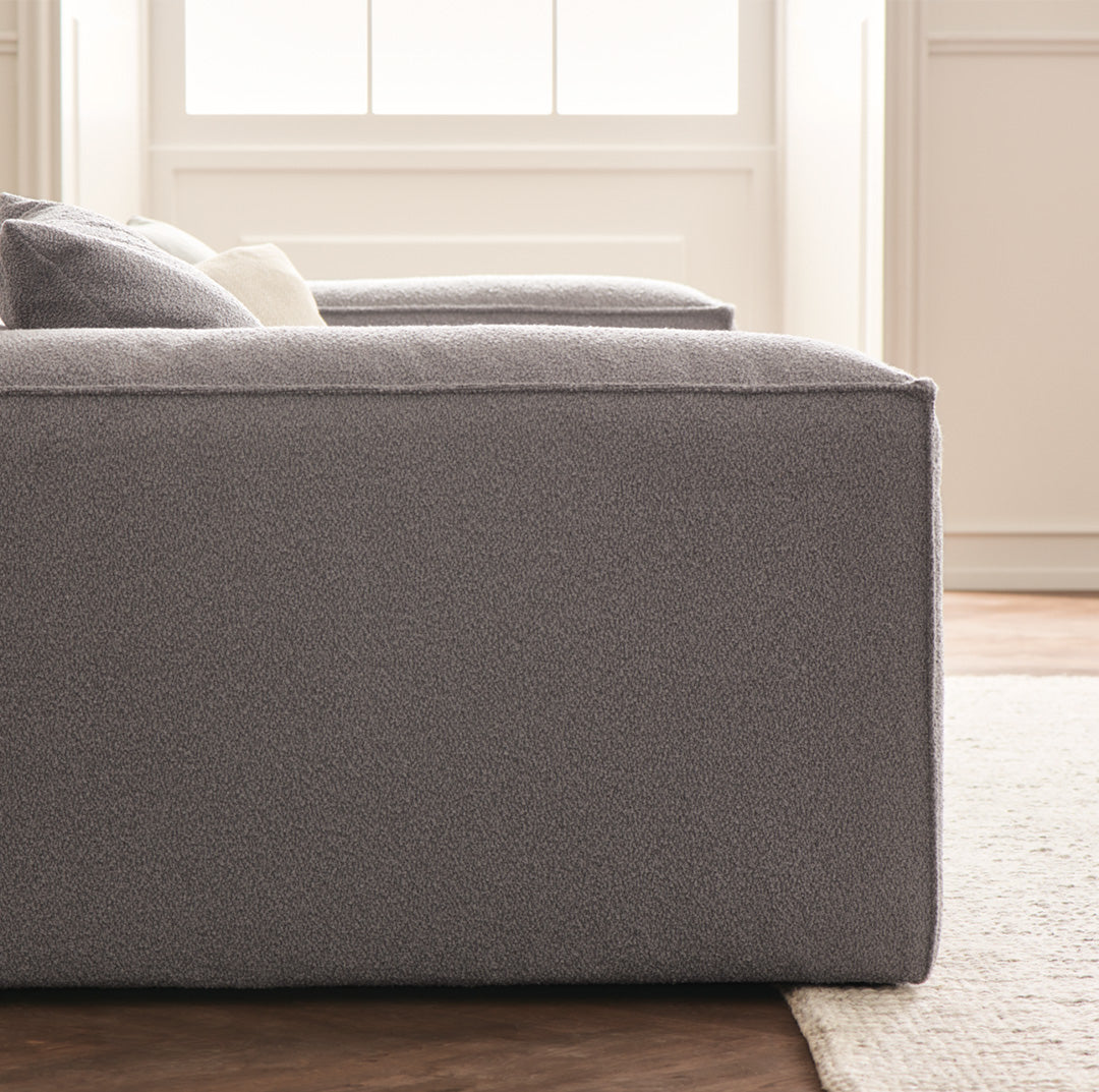 Gray upholstered sofa with a sleek, minimalist design and textured fabric, enhancing modern living room decor.
