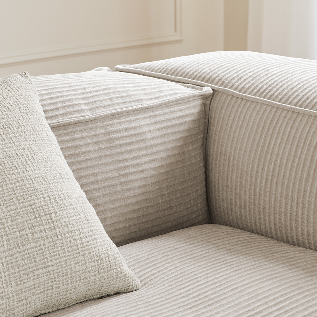 Beige couch with textured horizontal stripes and a square cushion featuring a woven pattern. Perfect for modern interiors.