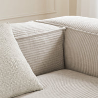 Beige couch with textured horizontal stripes and a square cushion featuring a woven pattern. Perfect for modern interiors.