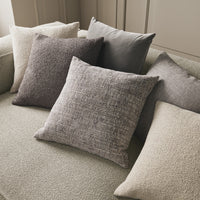 Assorted throw pillows in soft gray, beige, and textured patterns on a neutral green sofa. Perfect for modern decor.