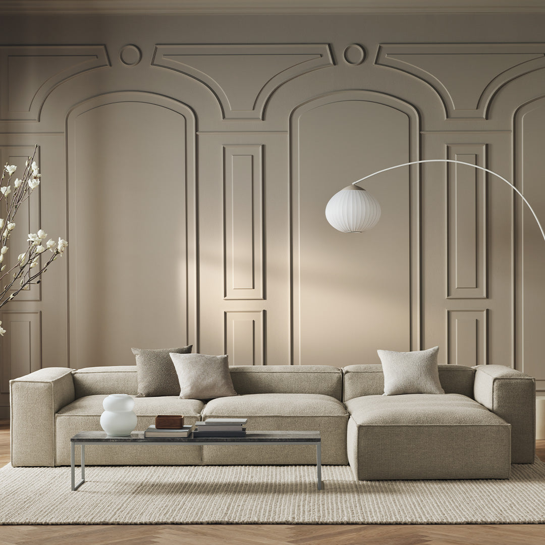 Beige sectional sofa with textured fabric, complemented by neutral pillows against a soft taupe wall.