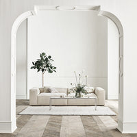 "Neutral beige sofa with white decorative elements, soft textures, and a light wood floor pattern."